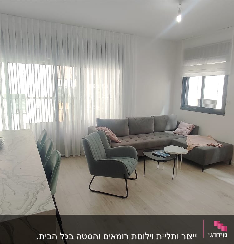 וילון לבן ארוך תלוי על חלון גדול בסלון